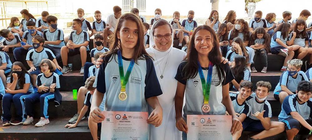 Ir. Rosicleide Defavari Diretora do Colégio Nossa Senhora das Graças entre os medalhistas Arthur Poças e Eduarda Tironi. Fotos: Carlos Roberto Francisquini/Jornal Circulandoaqui 