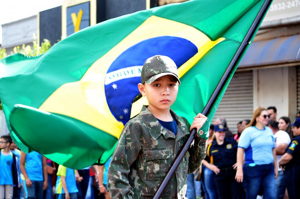 Menino vestido de soldado carrega bandeira do Brasil durante desfile da Independência em Cambará